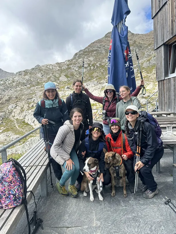 Gruppo davanti a una capanna con due cani